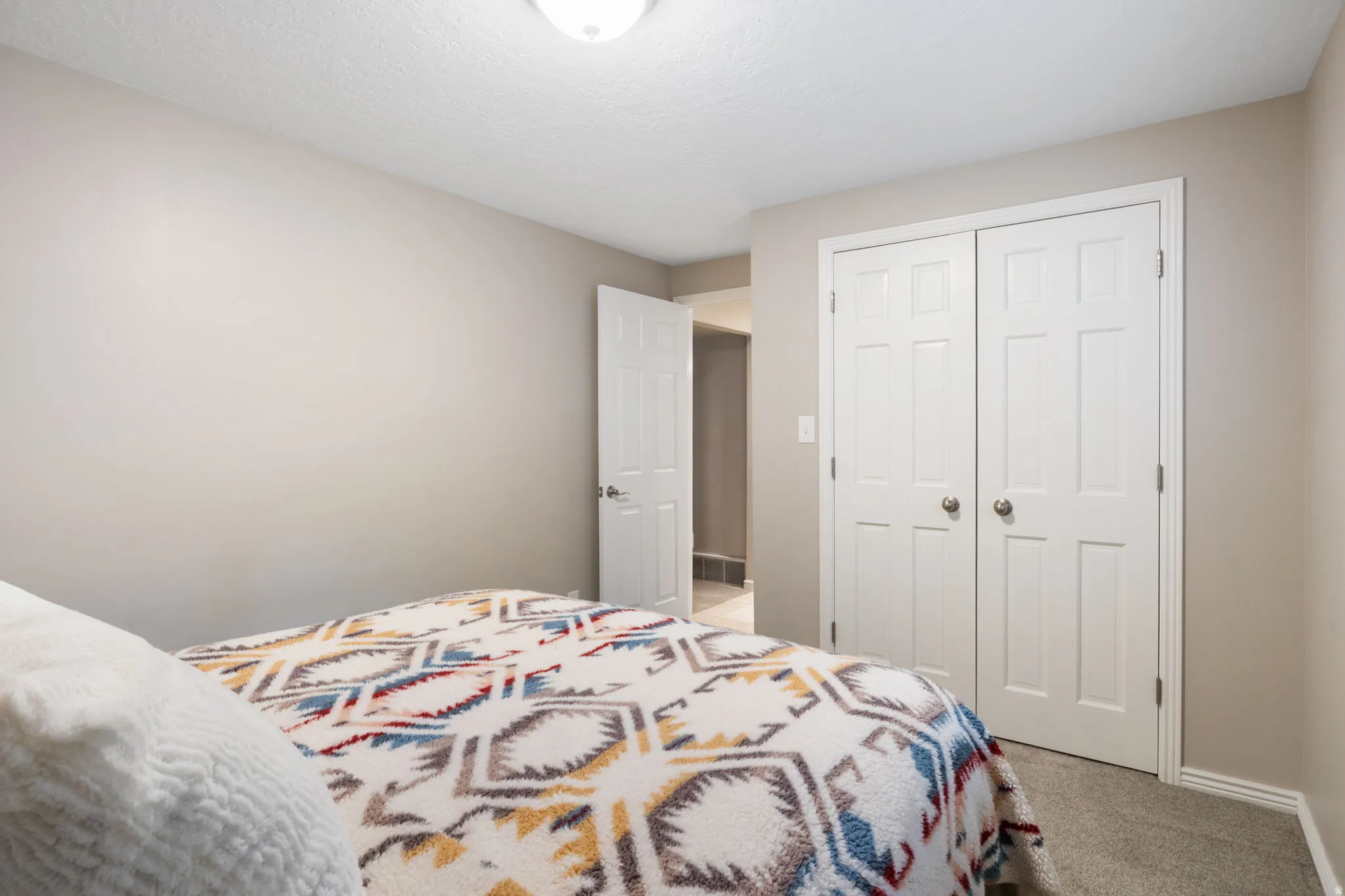 Room featuring light neutral wall paint, white trim, and textured carpeting