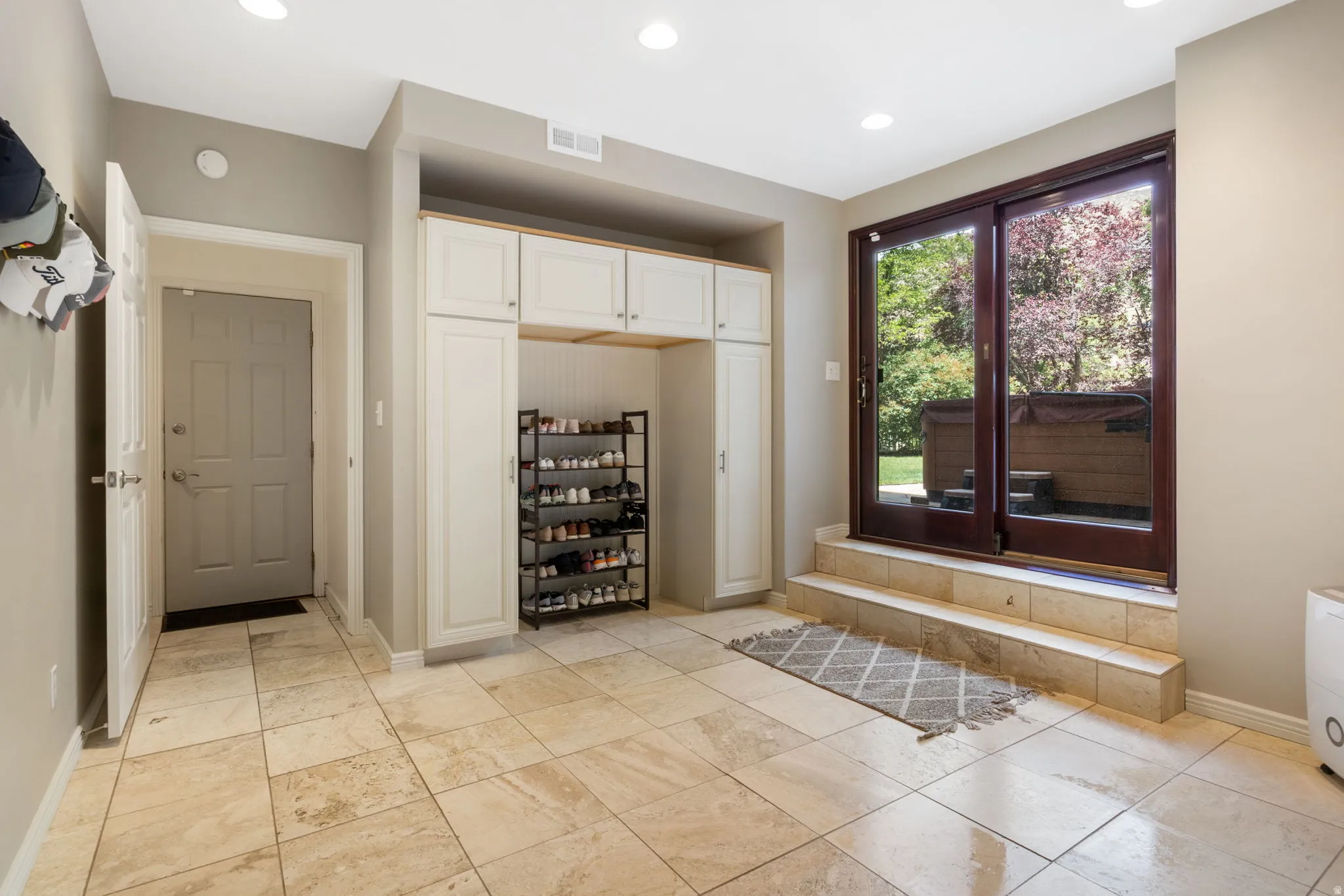 Tiled flooring extending to exterior access, built-in storage cabinetry, and recessed lighting