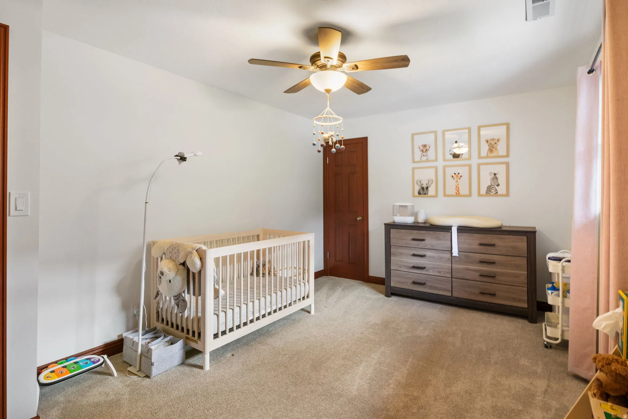 Spacious room featuring neutral carpeting, a ceiling fan with integrated lighting, and a solid wood interior door