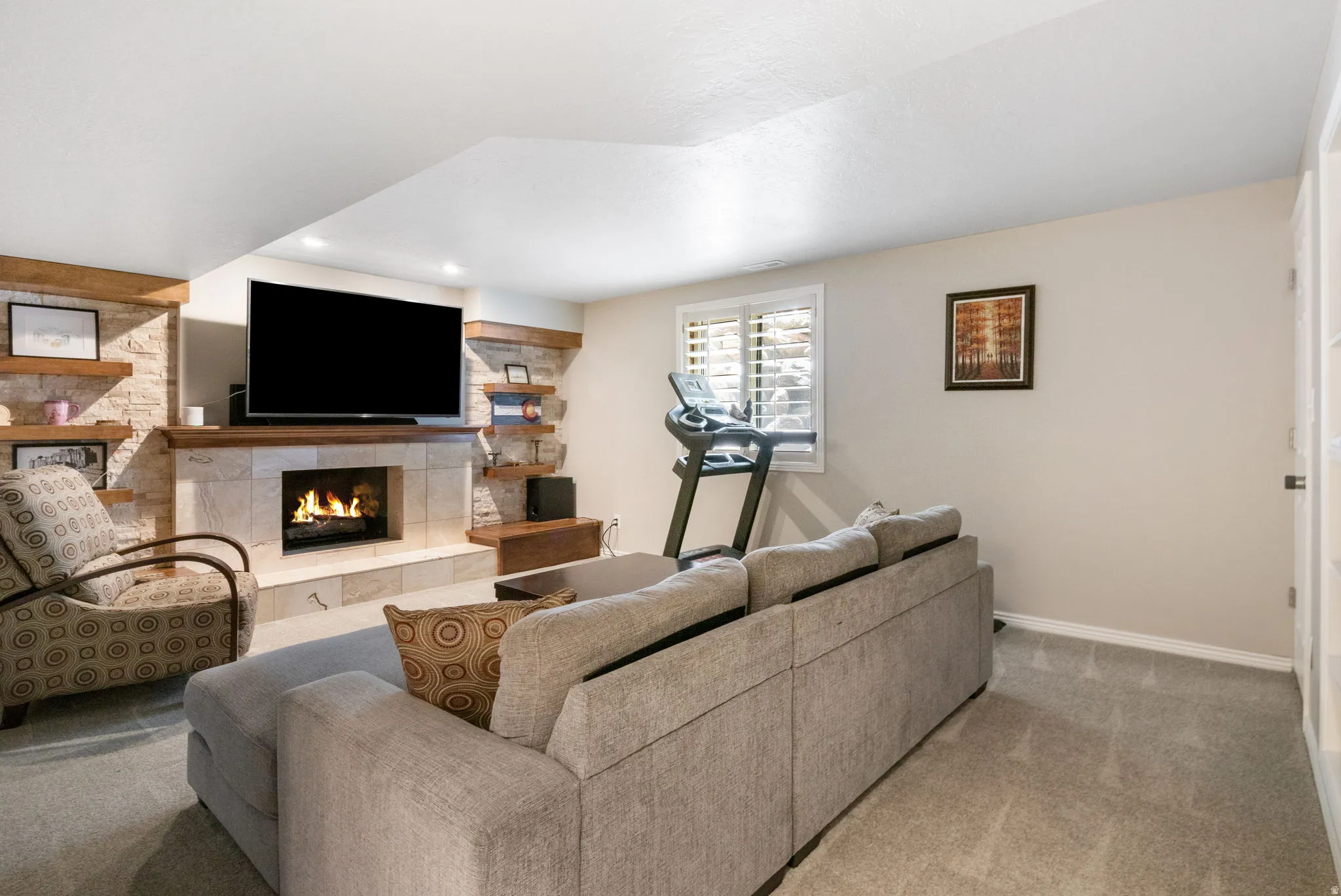 Living area featuring a stone-clad fireplace with a wood mantel, recessed lighting, and light gray carpeting