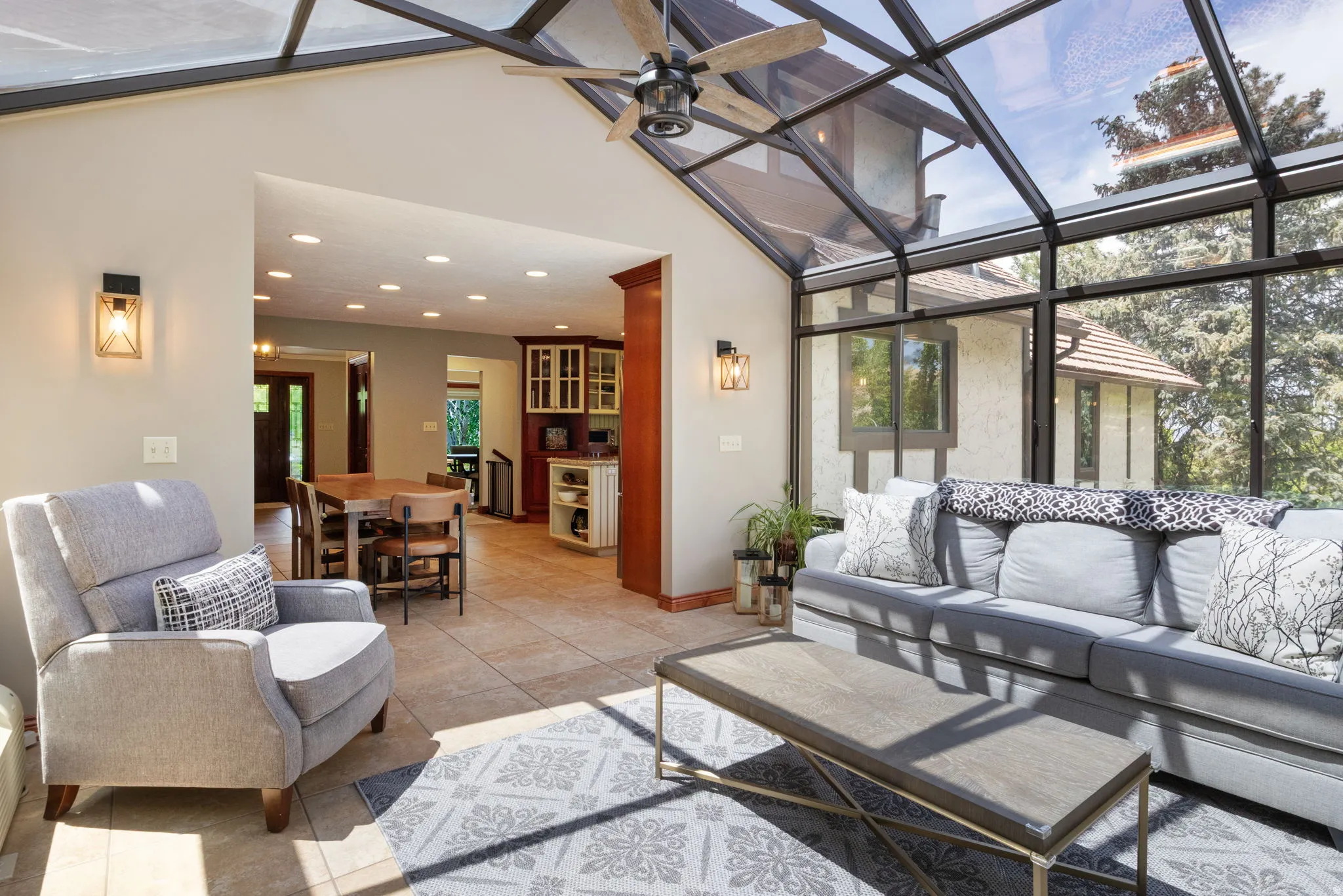 Sunroom featuring a full glass roof, wall-mounted sconces, and tile flooring