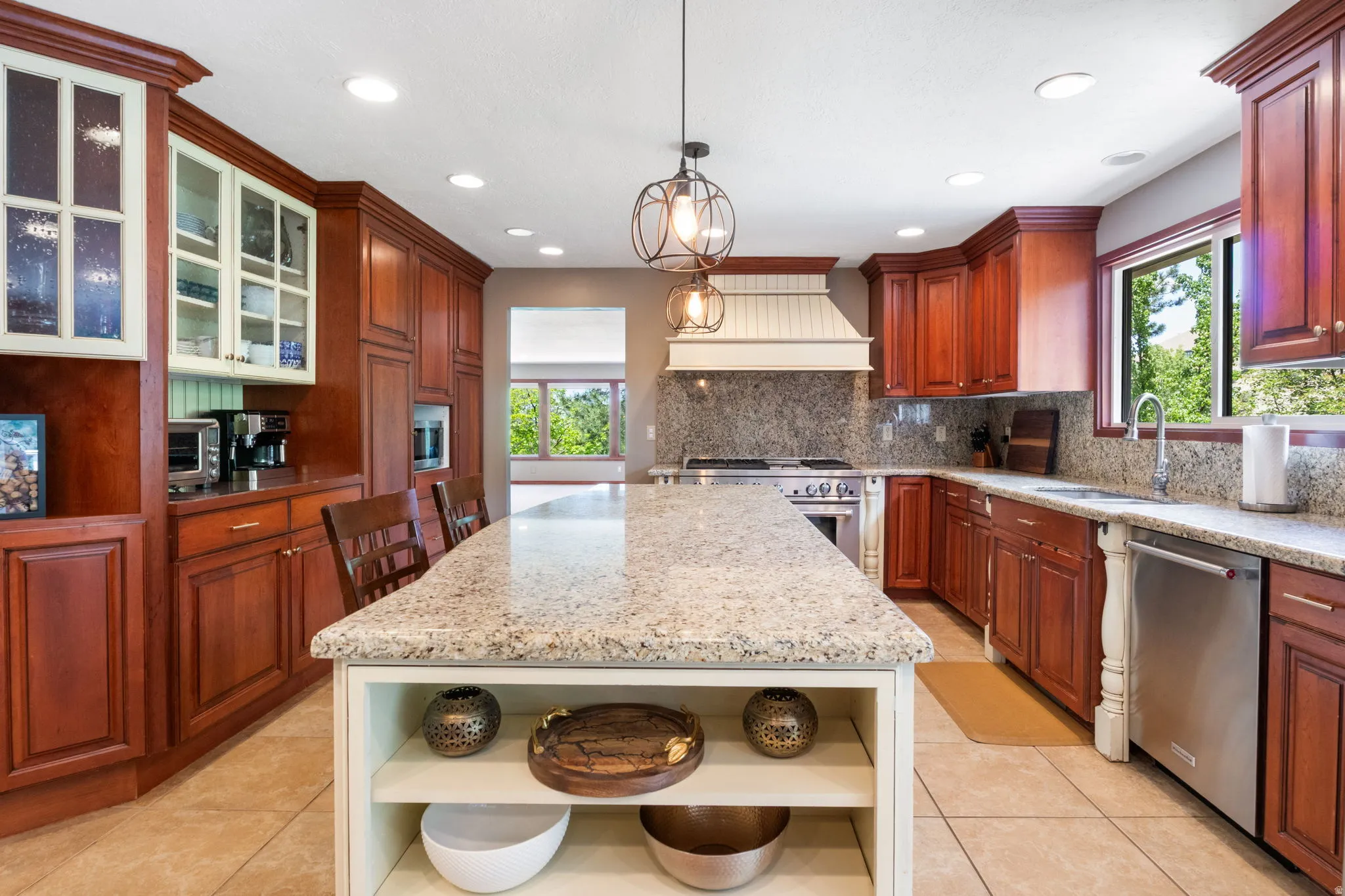 Kitchen featuring an expansive island with a light-colored countertop, rich wood cabinetry, stainless steel appliances, and a built-in range hood