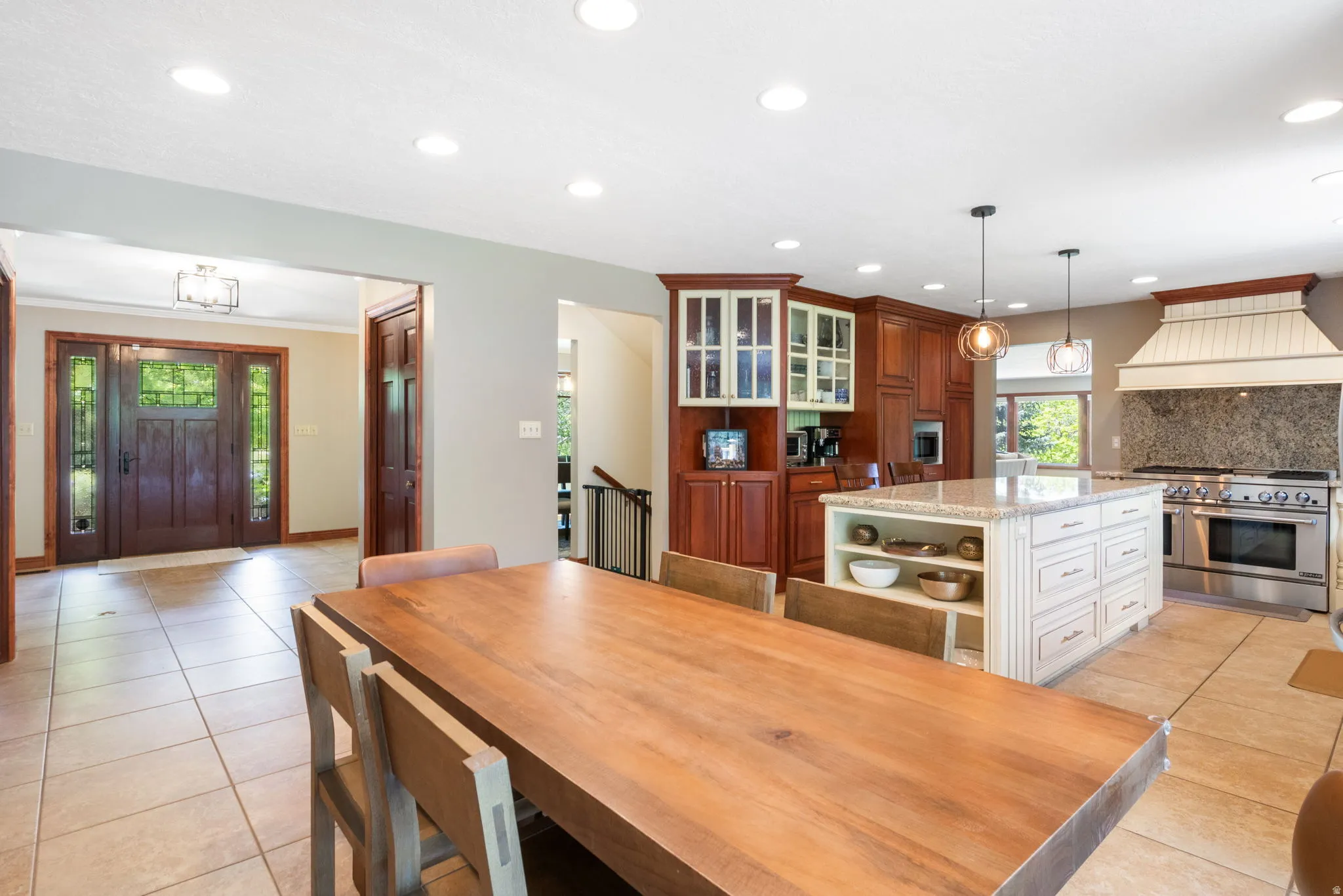 Open-concept kitchen and dining area featuring tile flooring, a large central island with integrated storage, and recessed lighting