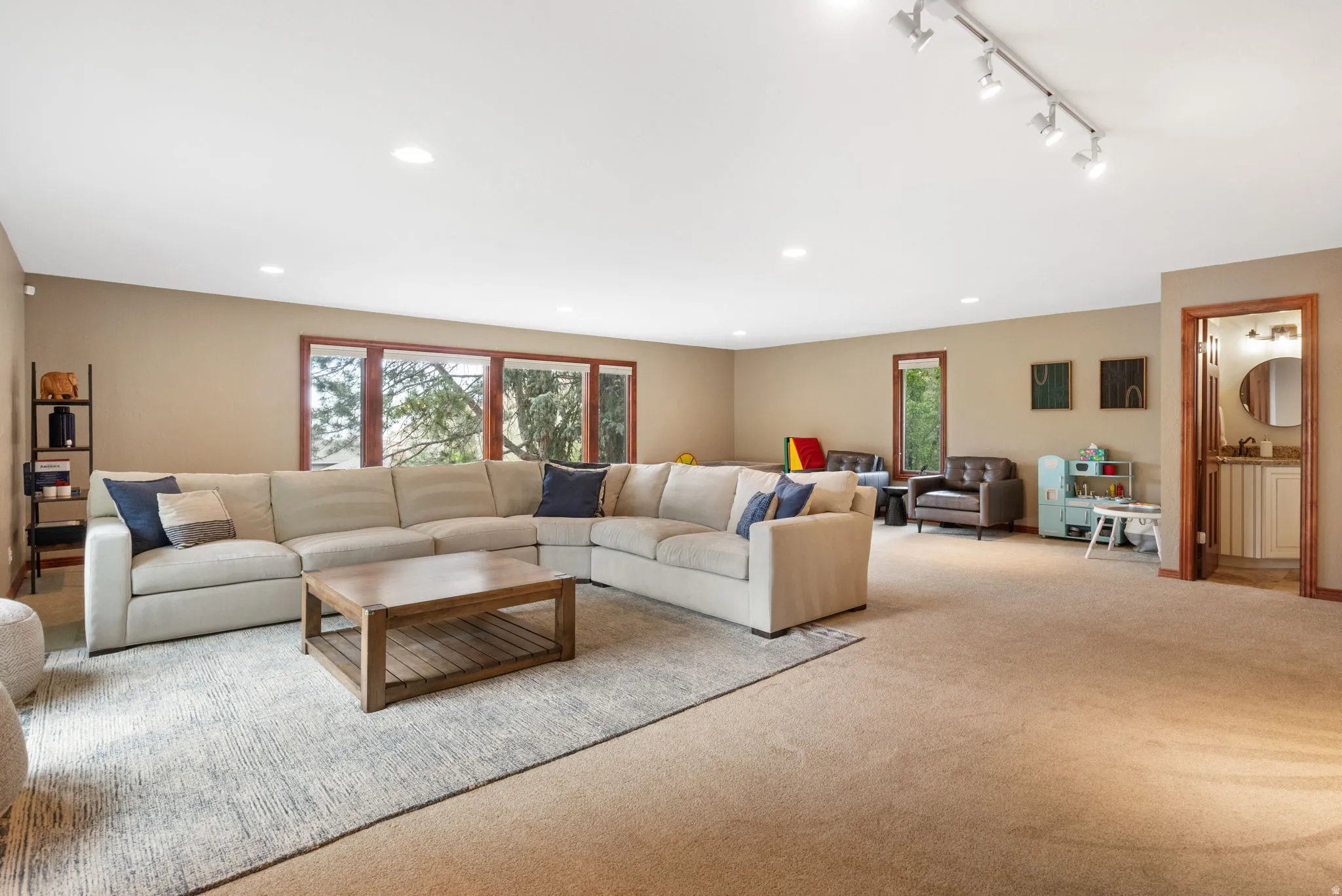 Spacious room featuring broad windows with wood trim, recessed lighting, and track lighting