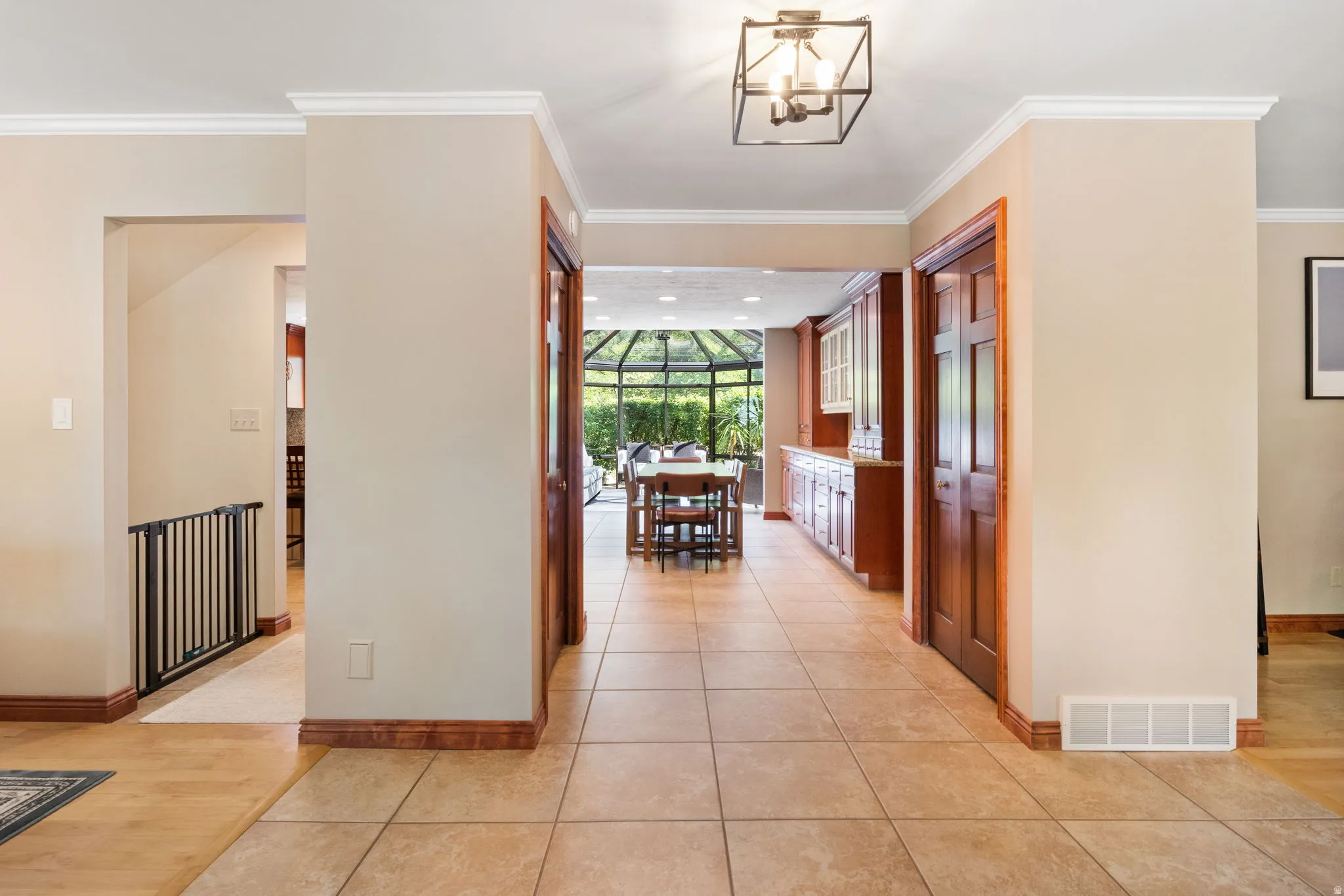 Tile flooring entry with crown molding accents, leading to a sunroom-style dining area with built-in cabinetry