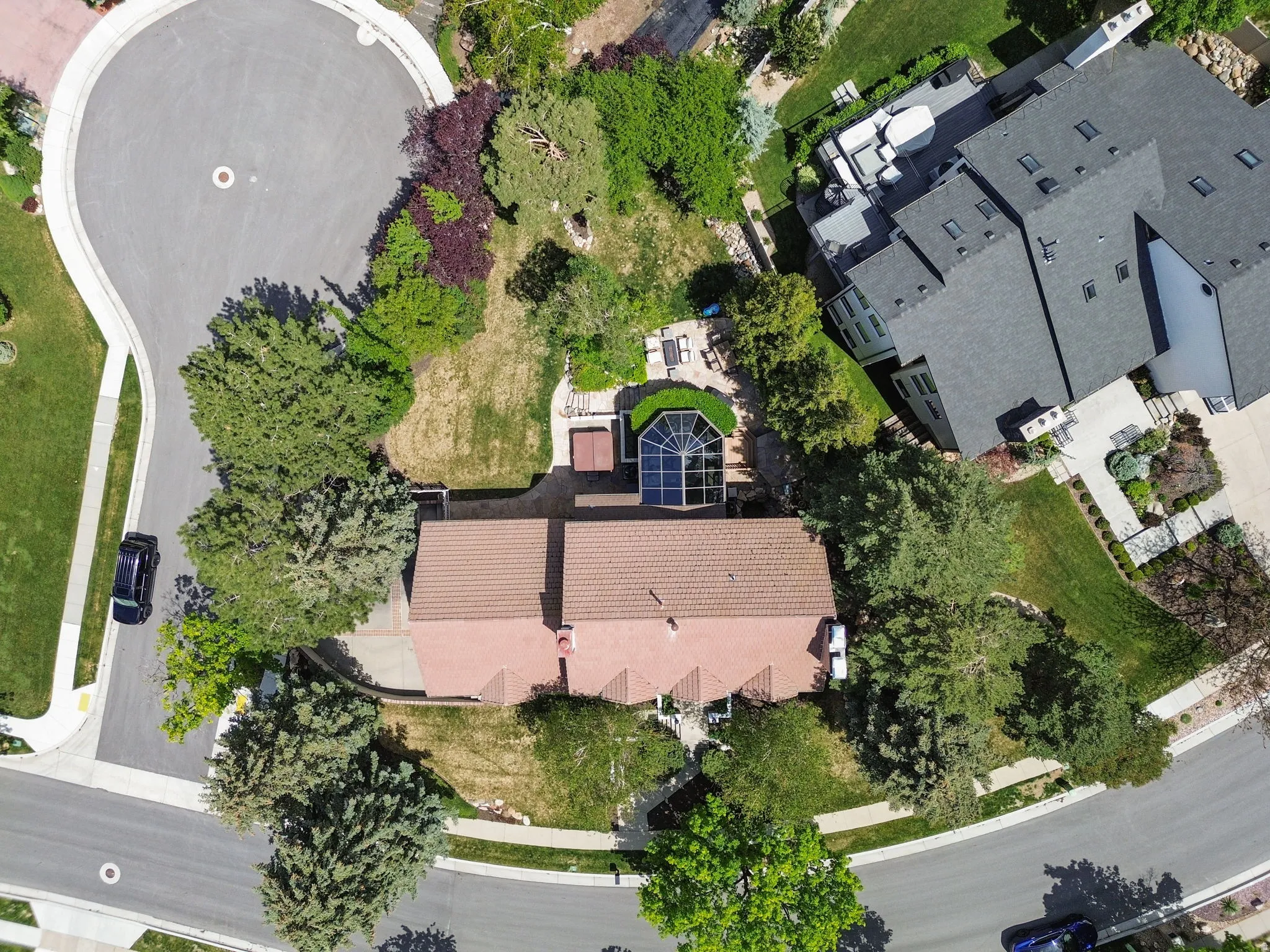Terracotta-style roofline residence featuring an expansive rear yard, mature landscaping, a sunroom with an arched window design, and an upper-level deck