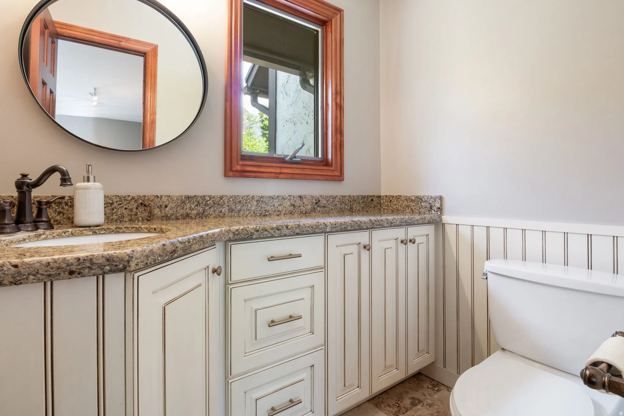 Powder Bath on main floor.  Bathroom featuring a stone countertop, integrated sink, and dark bronze-finish fixtures