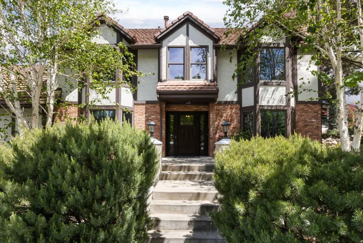 Tudor-style facade featuring brick and stucco accents, multi-pane windows, and a prominent dark wood entry door