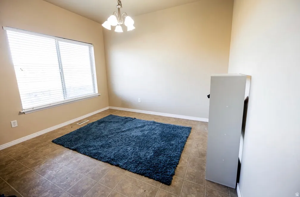 Interior space featuring a window with horizontal blinds, a ceiling-mounted light fixture, light-colored walls, and tile flooring
