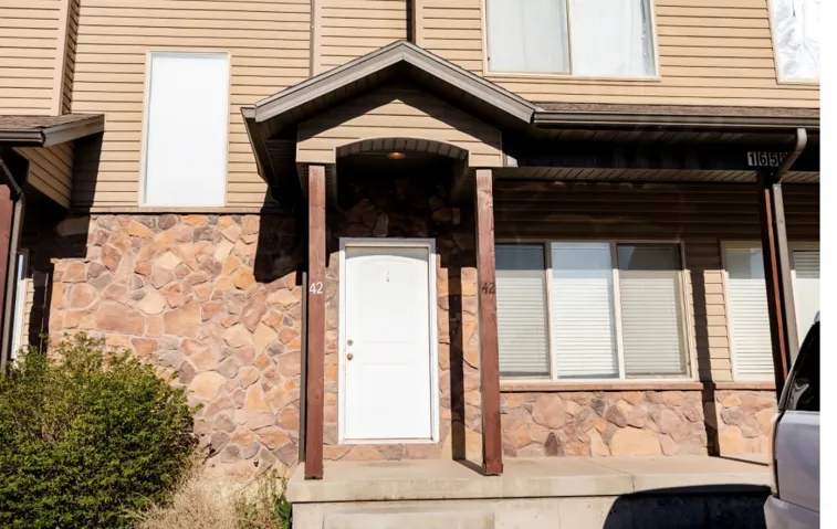 Entryway featuring a covered porch, stone veneer, and horizontal siding
