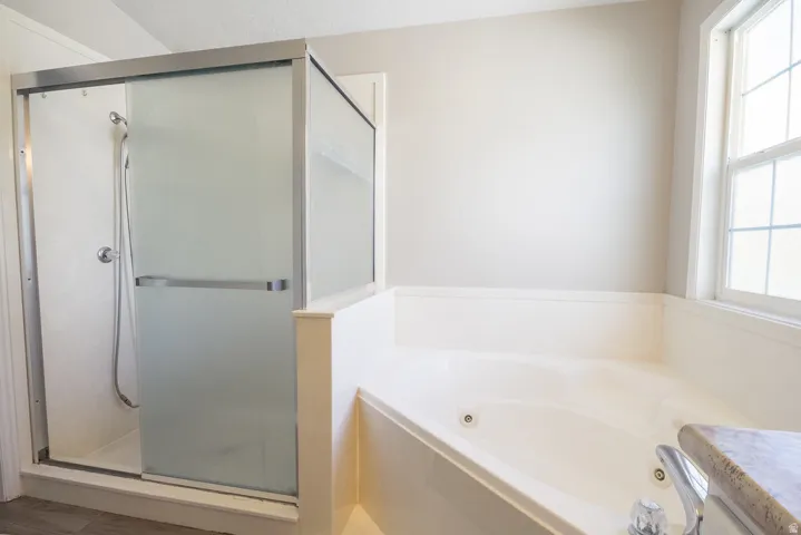 Shower enclosure with frosted glass sliding doors, built-in corner tub with jets, and a window with grid detailing