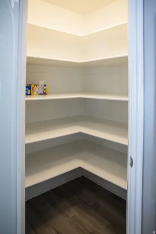 Corner pantry featuring multiple levels of shelving and wood-finish flooring