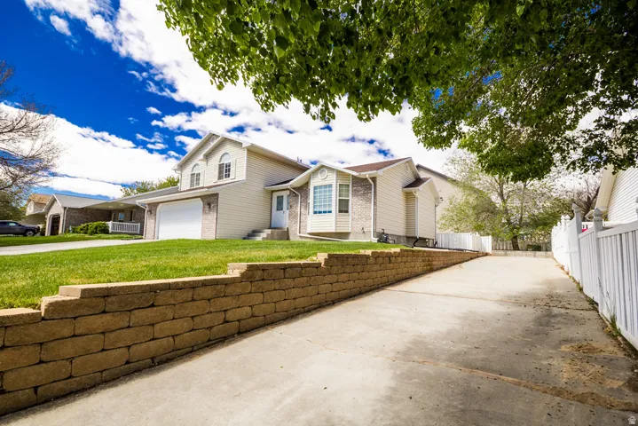 Split-level residence featuring a two-car garage, bay window, and a stone retaining wall bordering the driveway