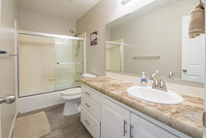 Bathroom featuring a single vanity with a patterned countertop, a built-in sink, and white cabinetry