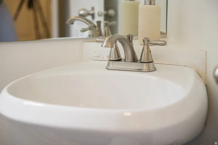 White ceramic sink with a brushed nickel faucet and a wall-mounted mirror