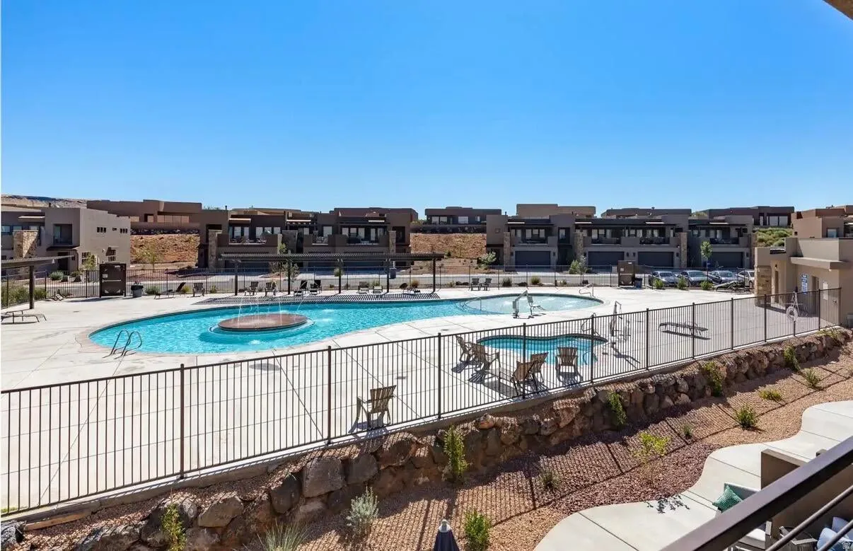Resort-style pool area featuring a large swimming pool with a circular water feature, an additional wading pool, and a surrounding concrete deck