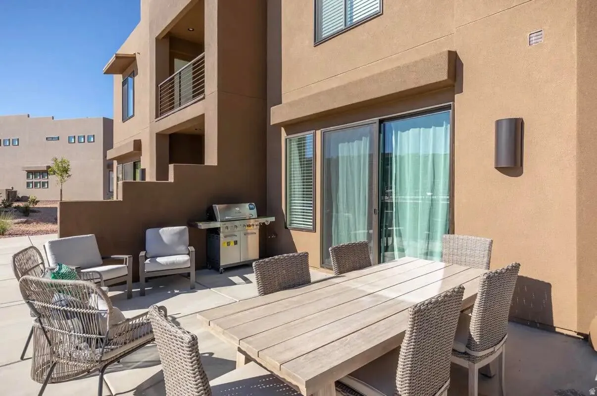 Private patio space featuring a sliding glass door entry, exterior wall sconce, and stucco exterior