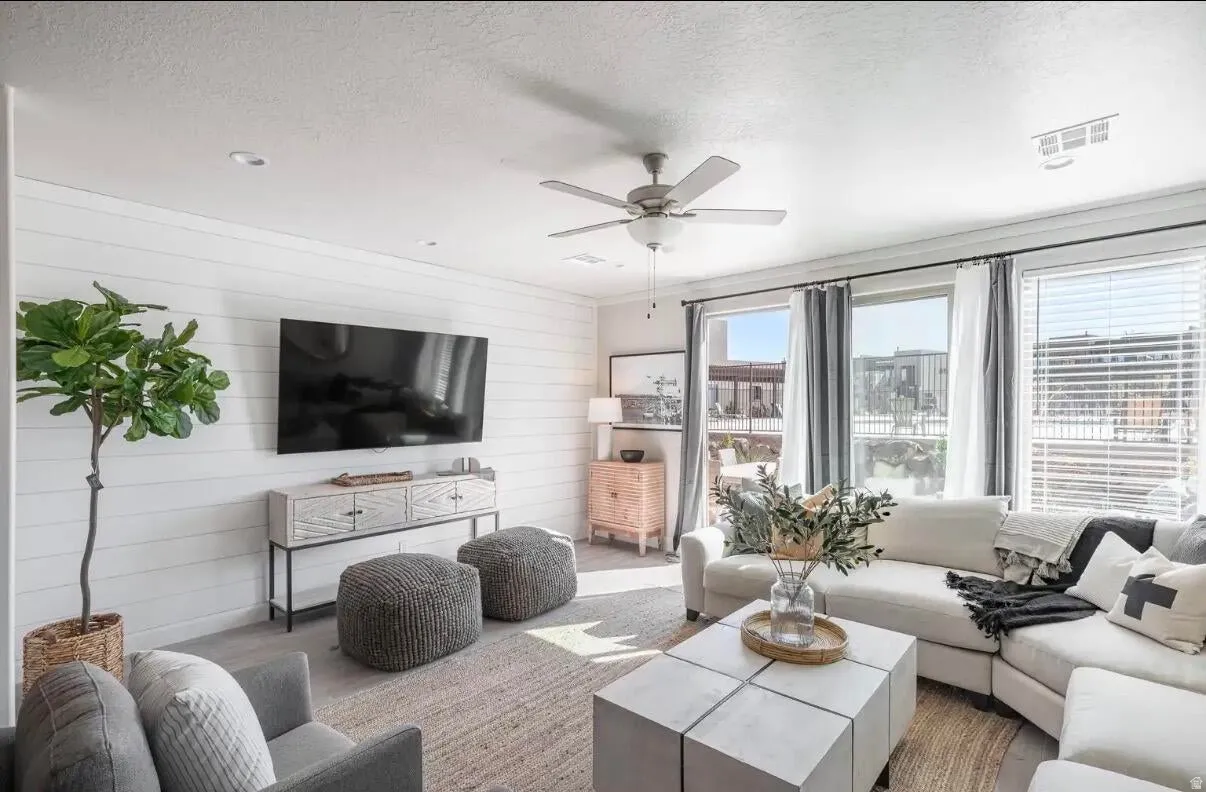 Spacious living area featuring a shiplap accent wall, multiple large windows, recessed lighting, and a ceiling fan