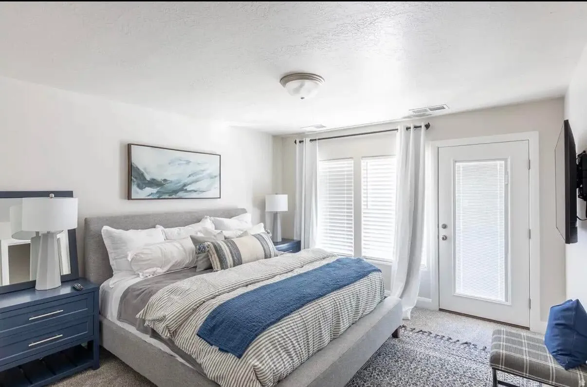 Bedroom featuring light gray carpet, an upholstered bed frame, and white walls