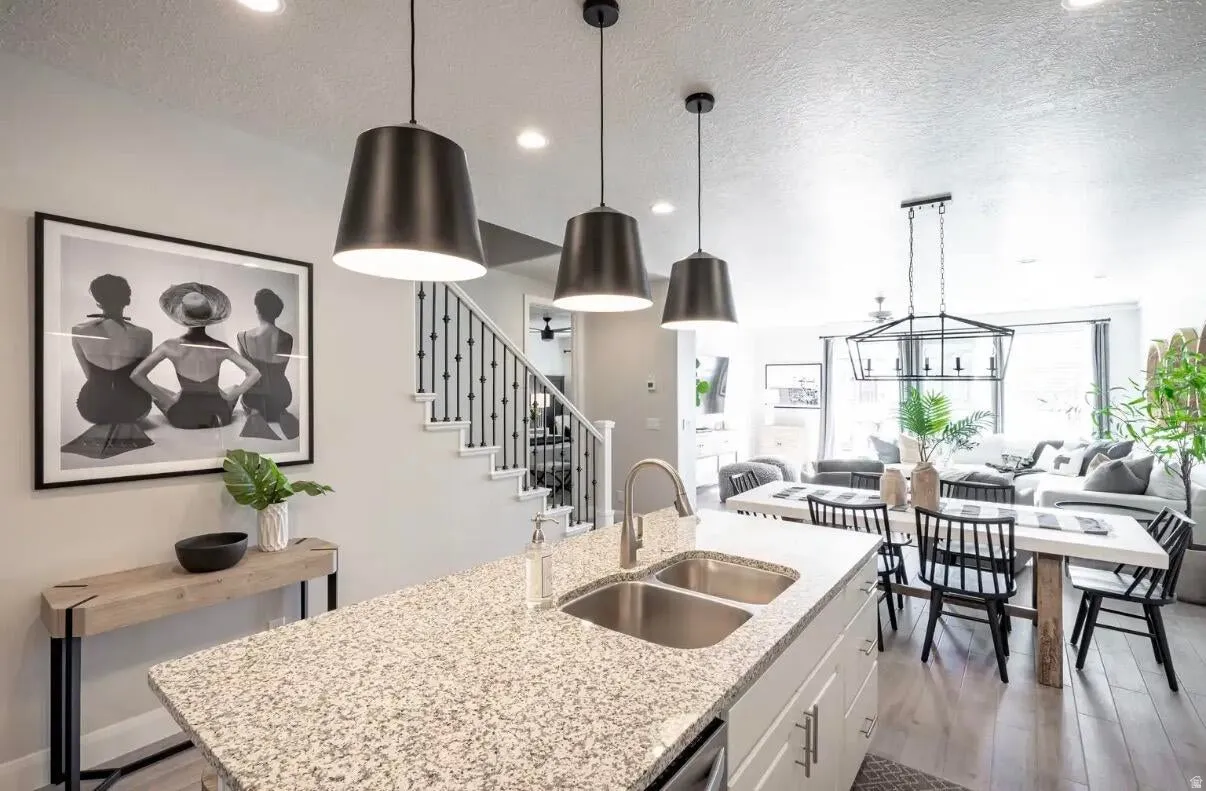 Open-concept living space featuring a kitchen island with a granite countertop and dual stainless steel sinks