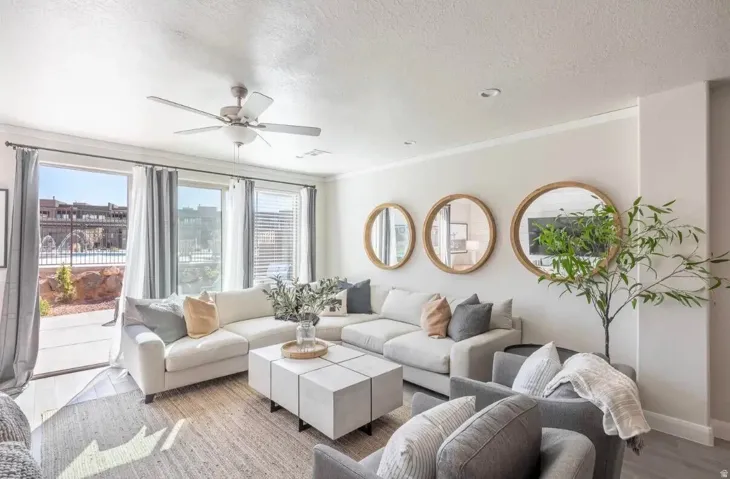 Spacious living area featuring large sliding glass doors, multiple windows with blinds, a ceiling fan, crown molding, and recessed lighting