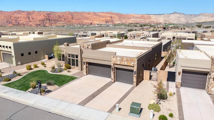 Contemporary exterior architecture featuring stucco and stone accents, two-car garage, and low-maintenance landscaping with rock beds and a shaped lawn
