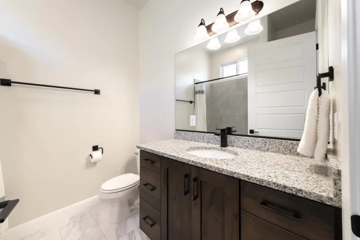 Bathroom vanity featuring a speckled countertop, undermount sink, and dark wood-finish cabinetry