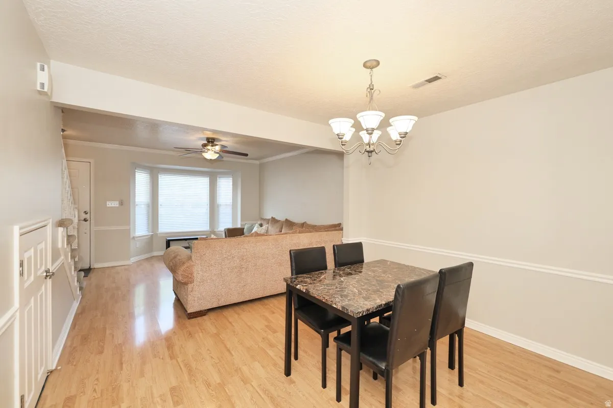 Dining area featuring a chandelier, wood-finish flooring, and crown molding