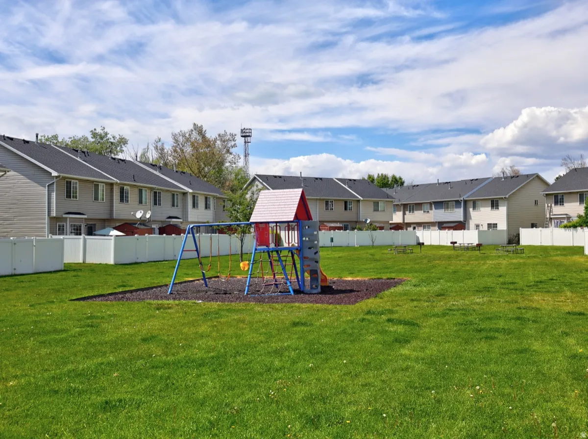 Community green space featuring a play structure with slide and swings, surrounded by a manicured lawn