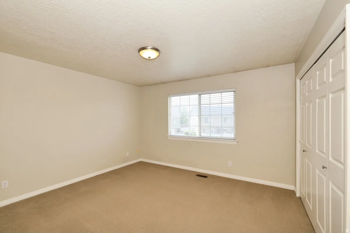 Spacious interior room featuring neutral wall tones, textured ceiling, and a flush-mount ceiling light fixture