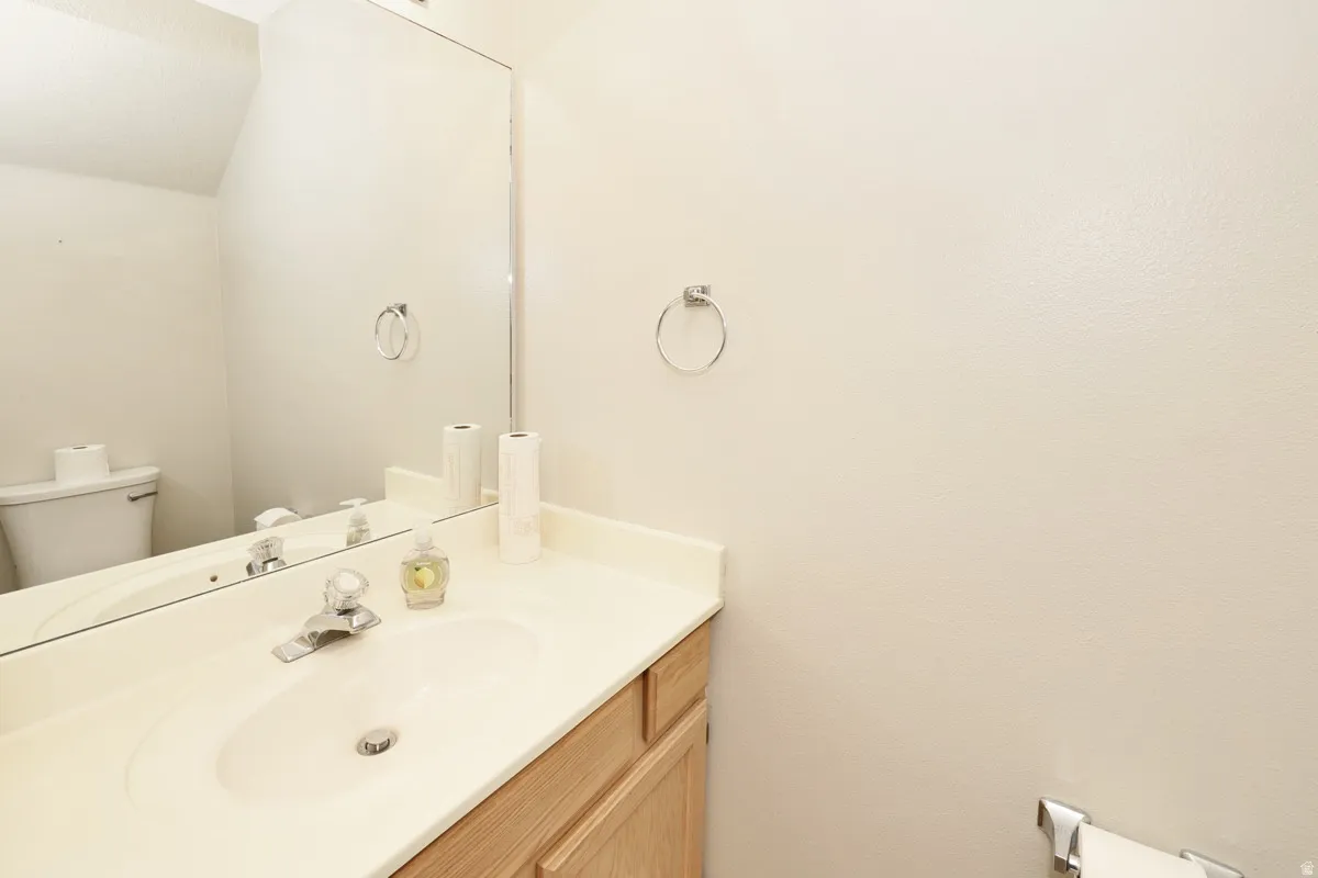 Bathroom vanity featuring an integrated sink, laminate countertop, natural wood-finish cabinetry, and a chrome faucet