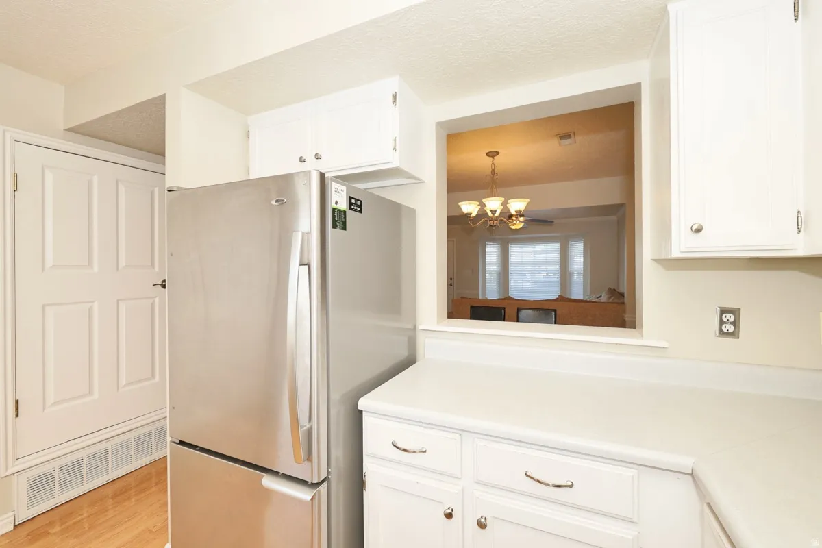 Kitchen featuring white cabinetry, light-toned countertops, and a stainless steel refrigerator