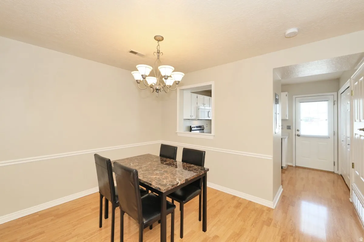 Dining space featuring wood-finish flooring, a decorative chandelier, and a pass-through window
