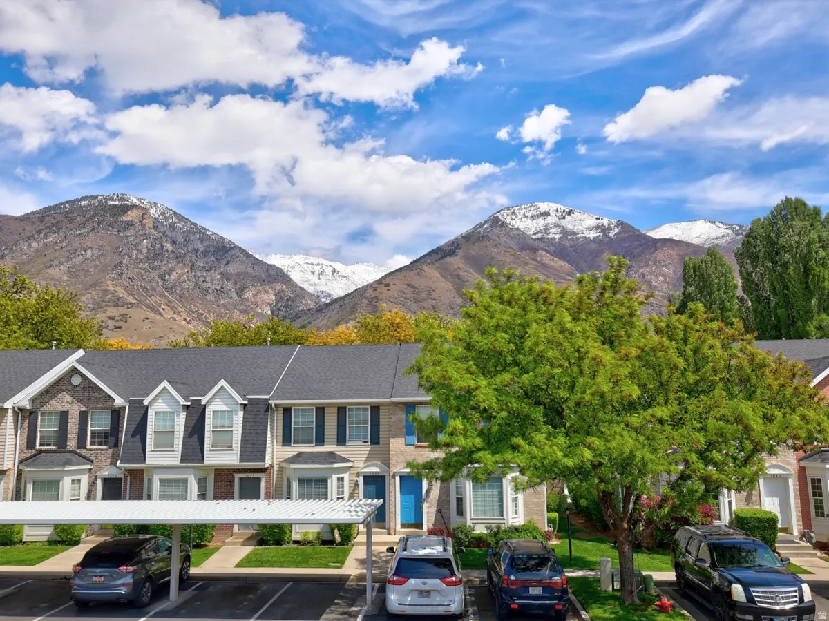 Townhome community featuring covered parking, brick and siding exteriors, dormer windows, and mature landscaping