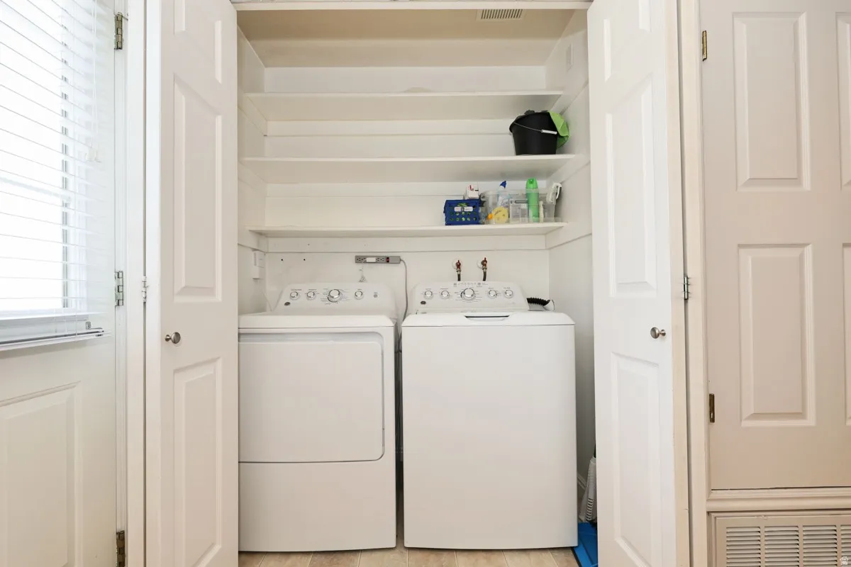 Dedicated laundry closet featuring a built-in washer and dryer, white shelving, and wood-finish flooring