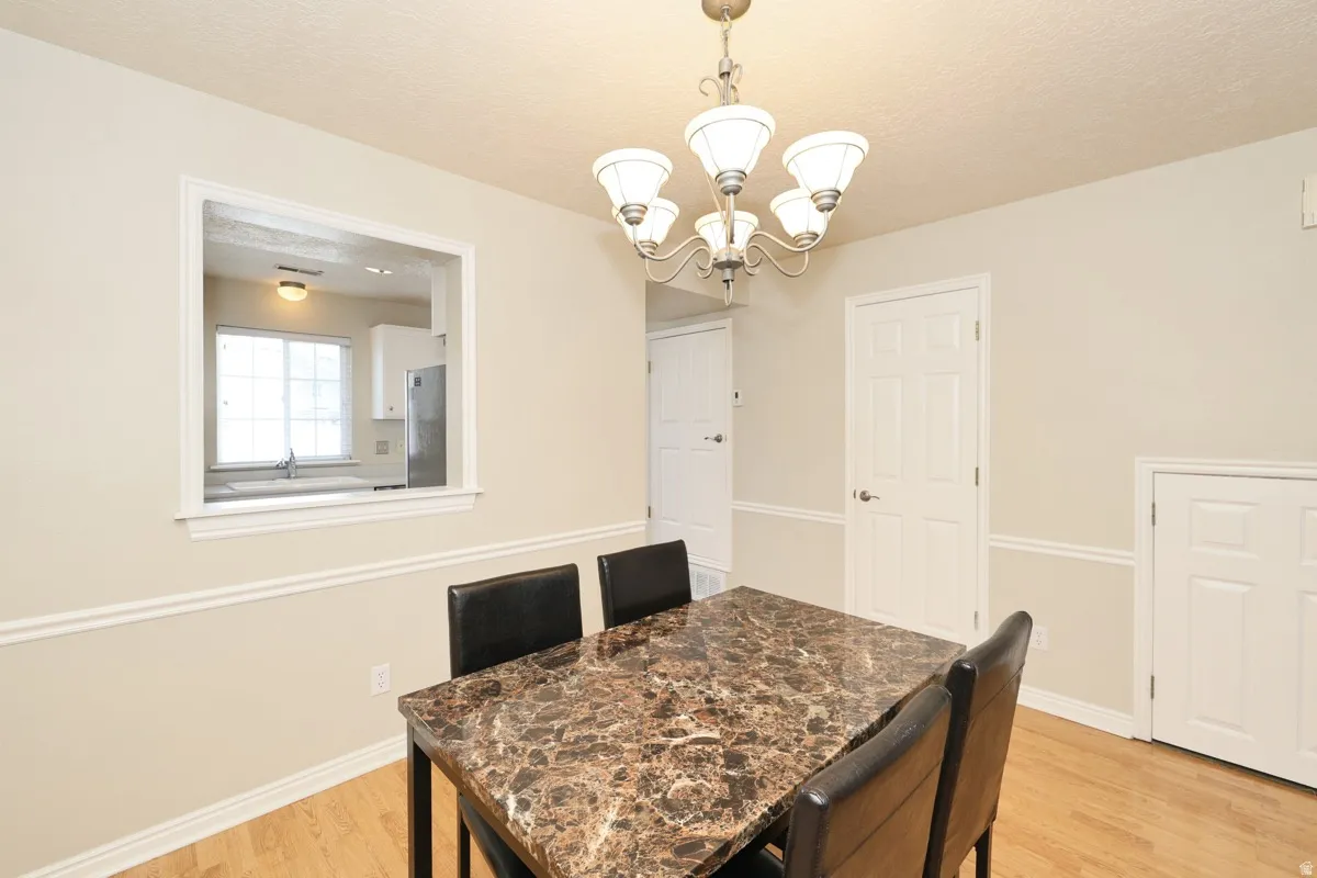 Dining area featuring light wood-finish flooring, a decorative chandelier, and chair rail molding
