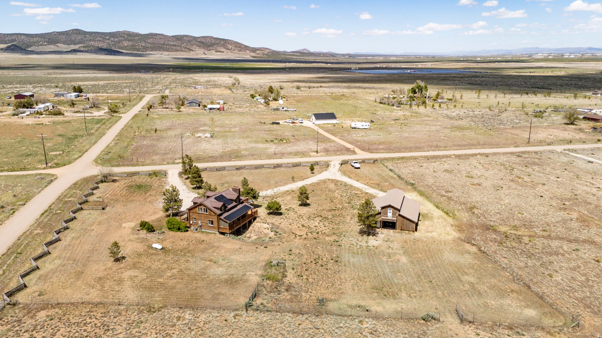 Aerial perspective showcasing two distinct residential properties amidst a vast, open landscape