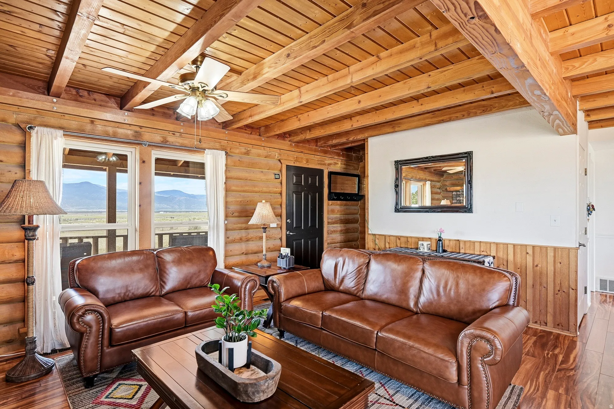 Interior living space featuring wood-finish flooring, wood-paneled walls, and an exposed beam ceiling