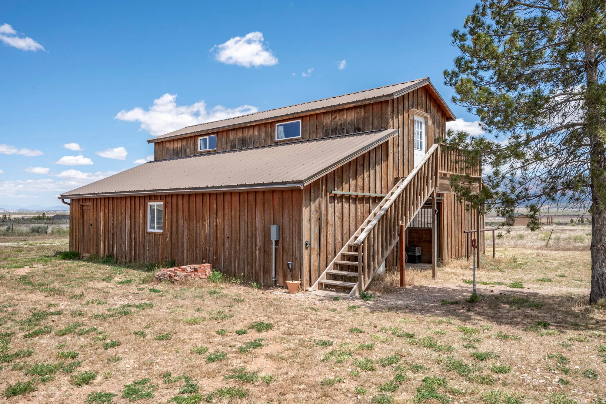 Wood-sided structure with a metal roof and an exterior staircase leading to a second-story entry