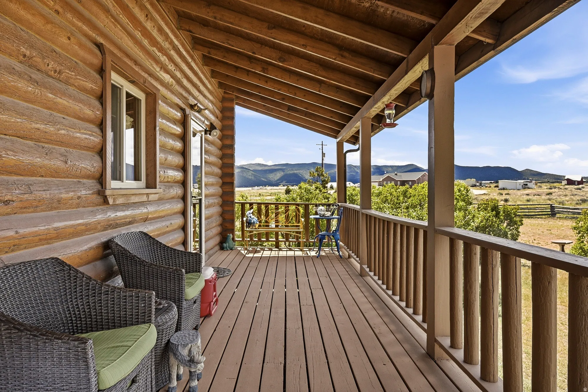 Expansive covered porch featuring wood-finish flooring, log siding, and a rustic wooden railing