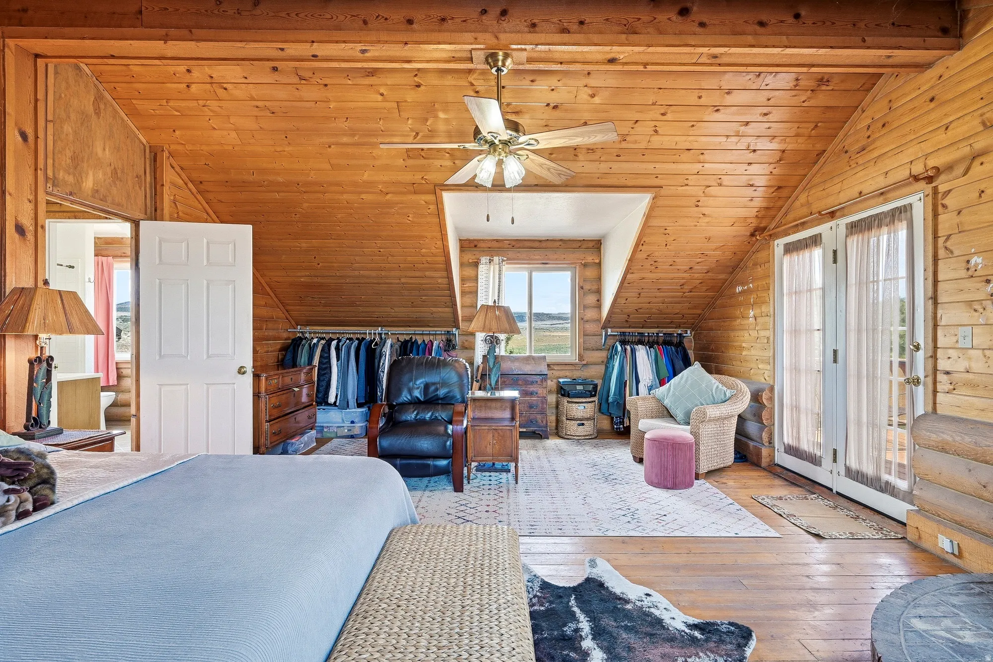 Spacious room featuring wood-finish walls and ceilings, wide plank flooring, and a ceiling fan