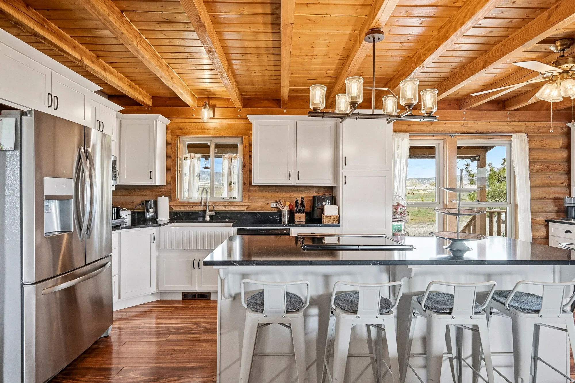 Kitchen featuring a wood-finish plank ceiling with exposed beams, white cabinetry, dark countertops, and stainless steel appliances