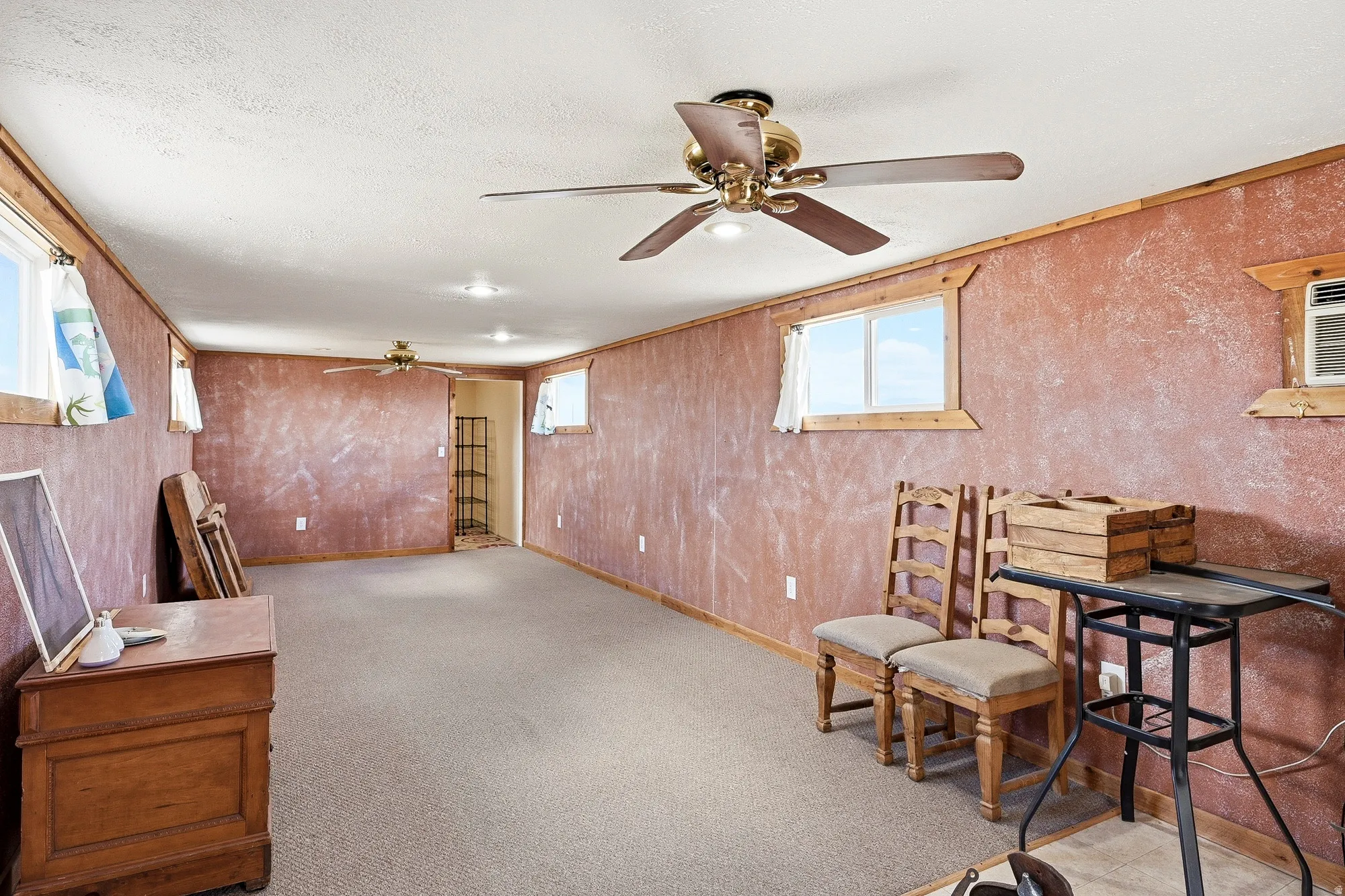 Spacious interior room featuring textured walls, multiple windows, recessed lighting, and ceiling fans