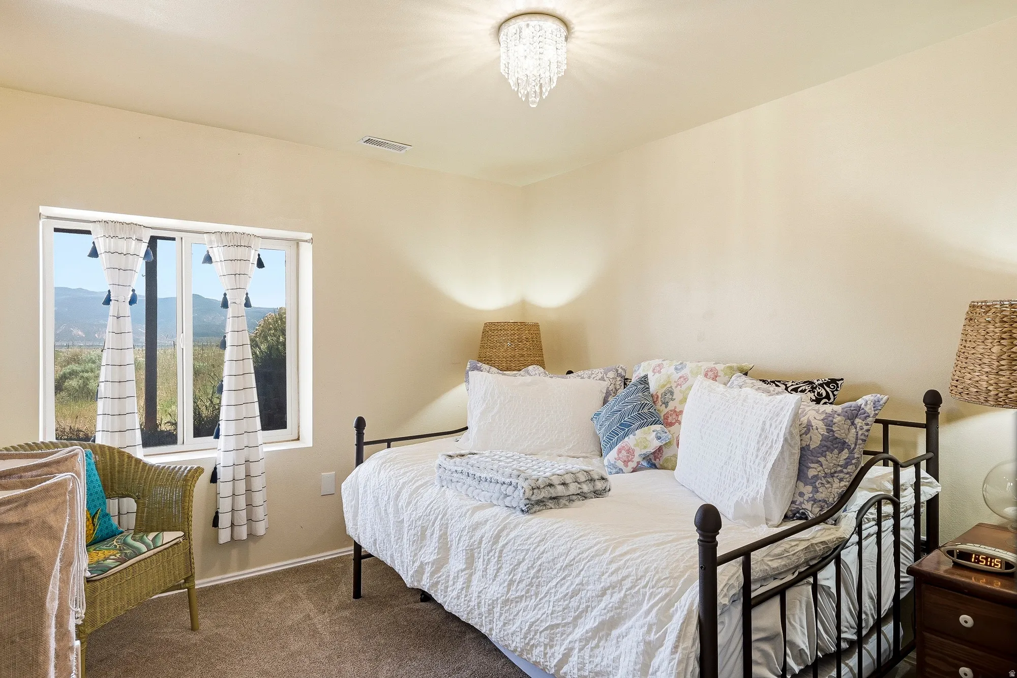 Carpeted room with a crystal chandelier, neutral painted walls, and a window framing a mountain backdrop