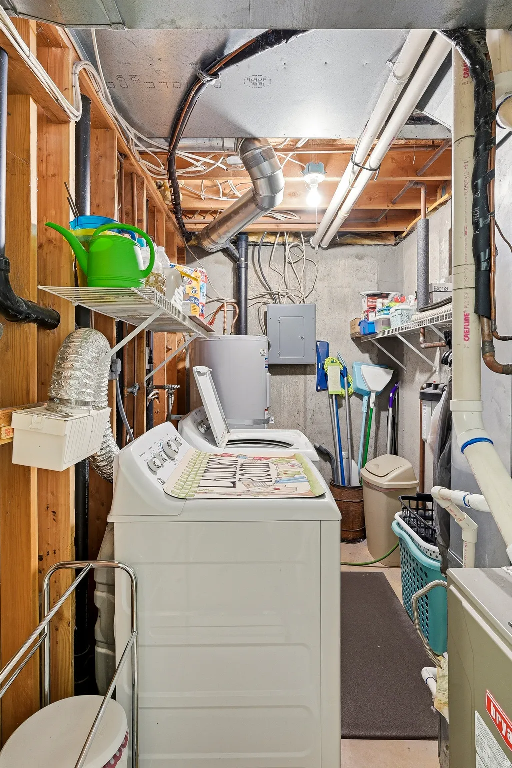 Utility area with exposed wood framing, concrete walls, and overhead lighting