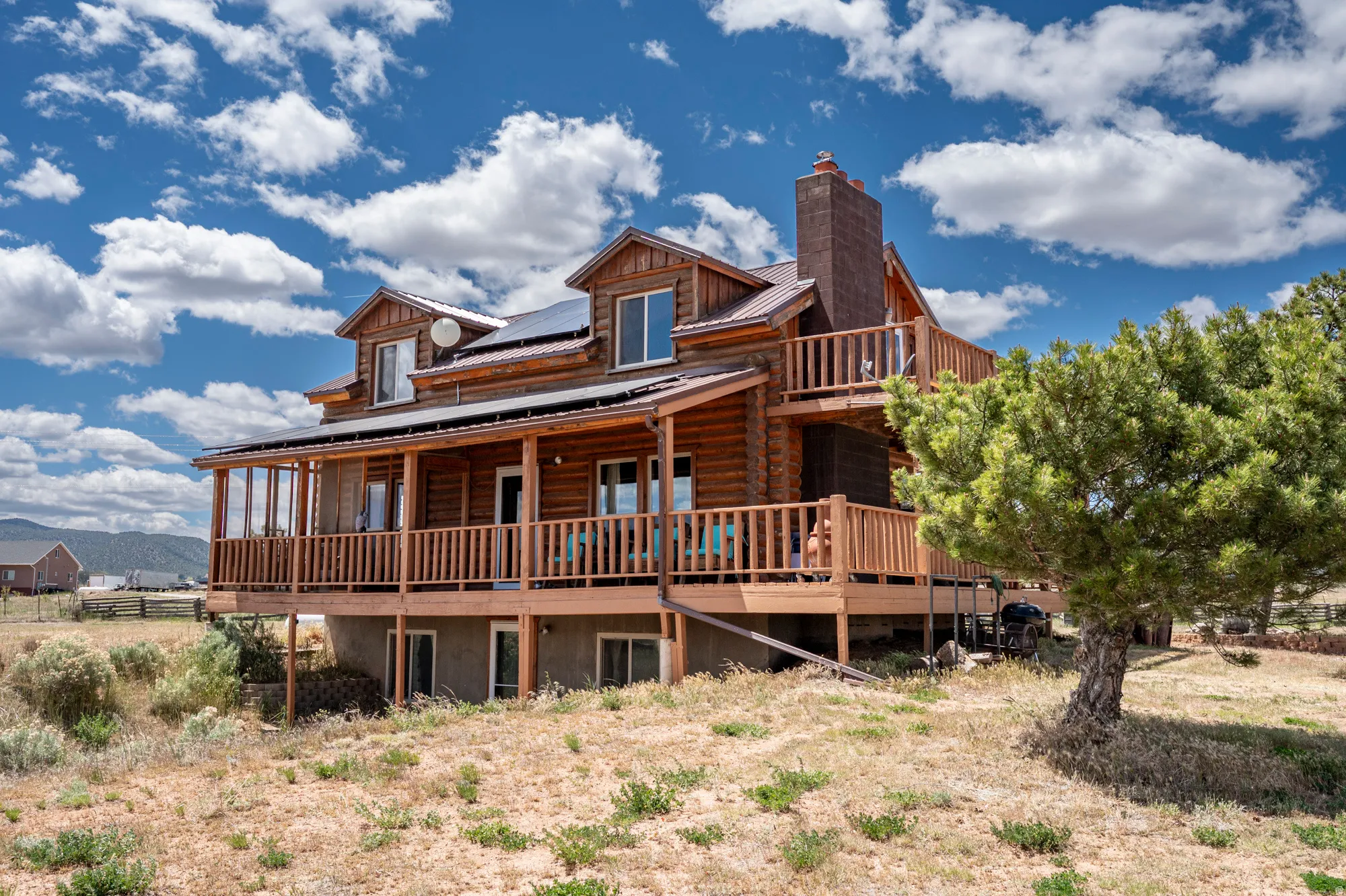 Log cabin exterior featuring multiple balconies, a wrap-around porch, and dormer windows