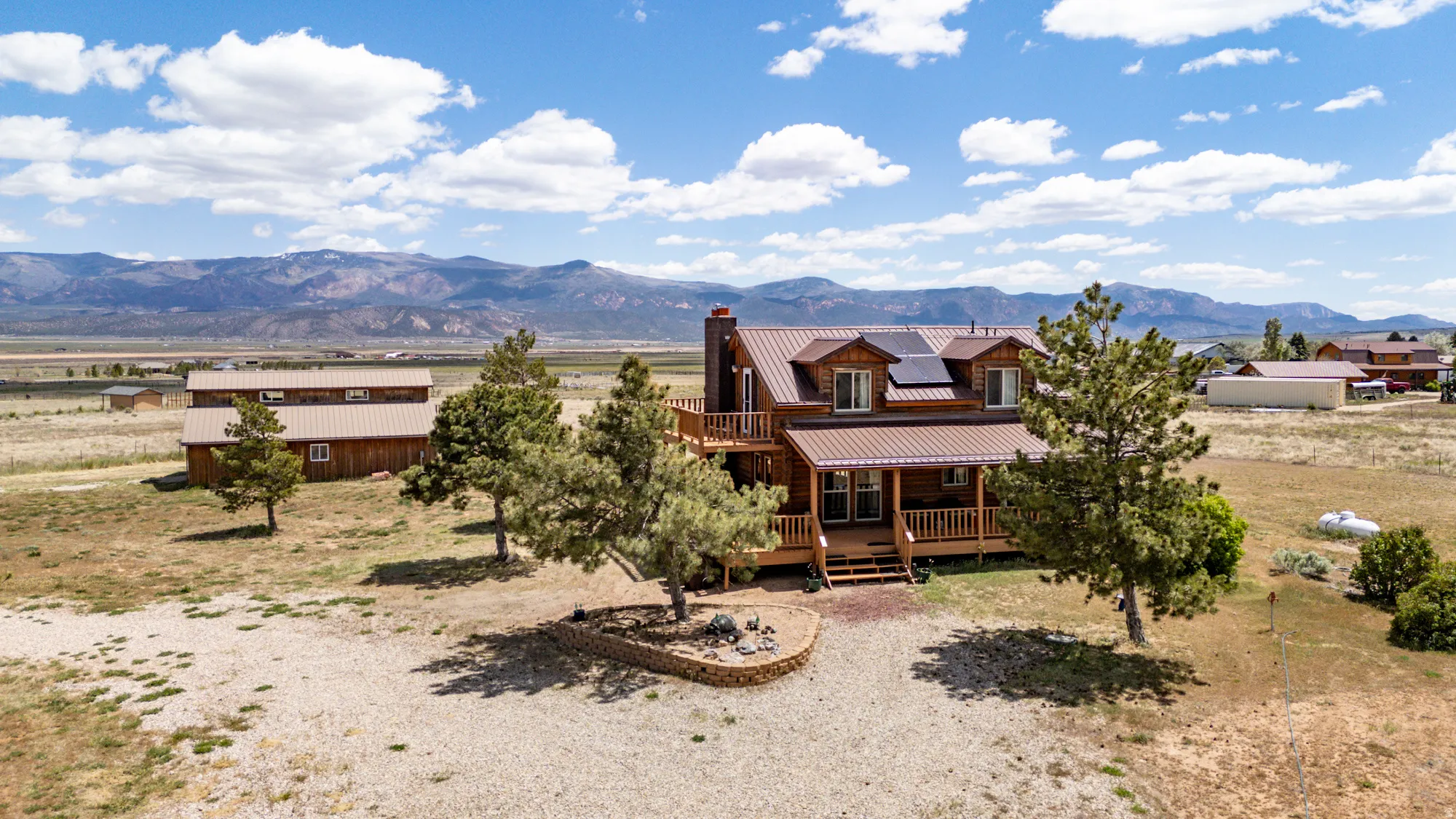 Log-style residence featuring a brown metal roof, expansive deck, and solar panels