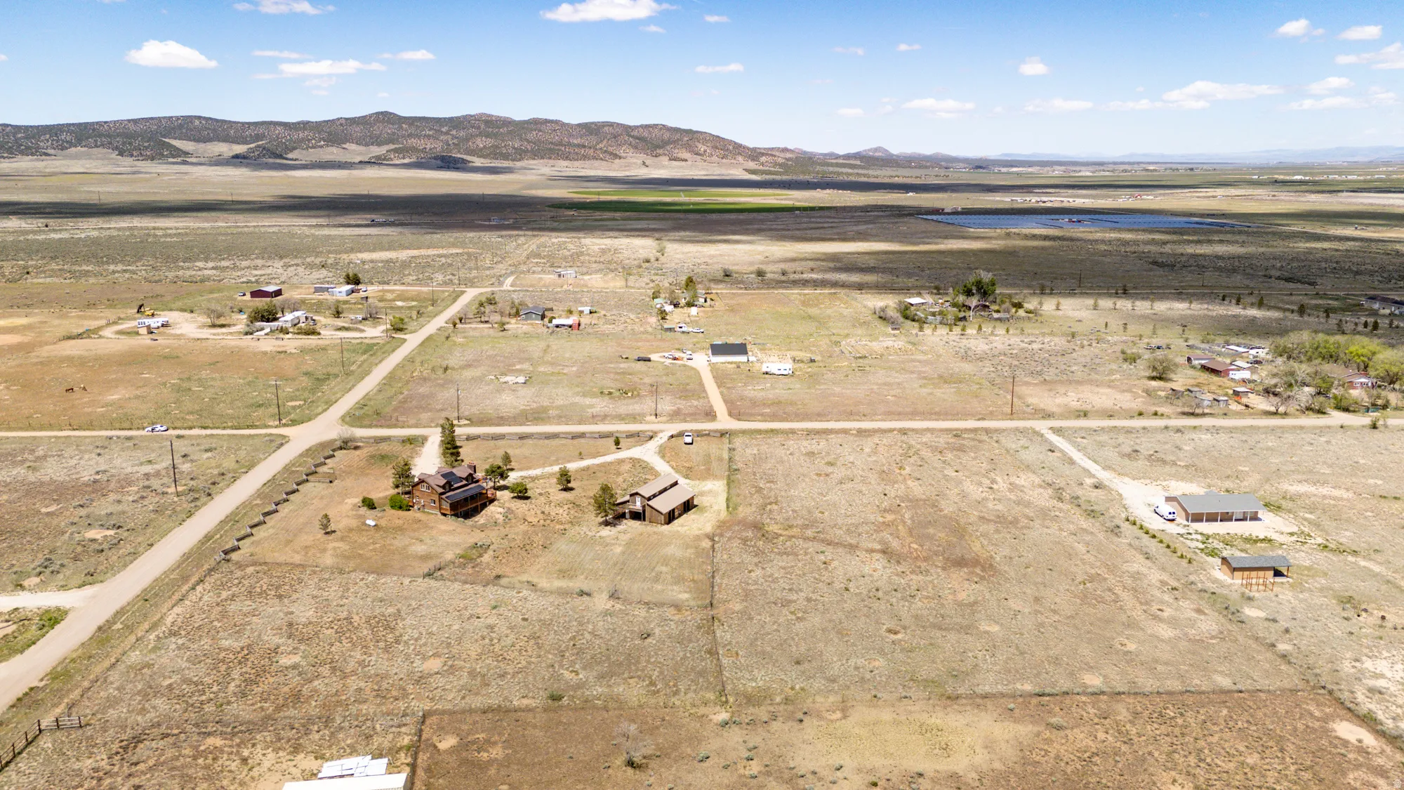 Expansive land parcel featuring multiple structures, including a main residence with a dark roof and an additional outbuilding