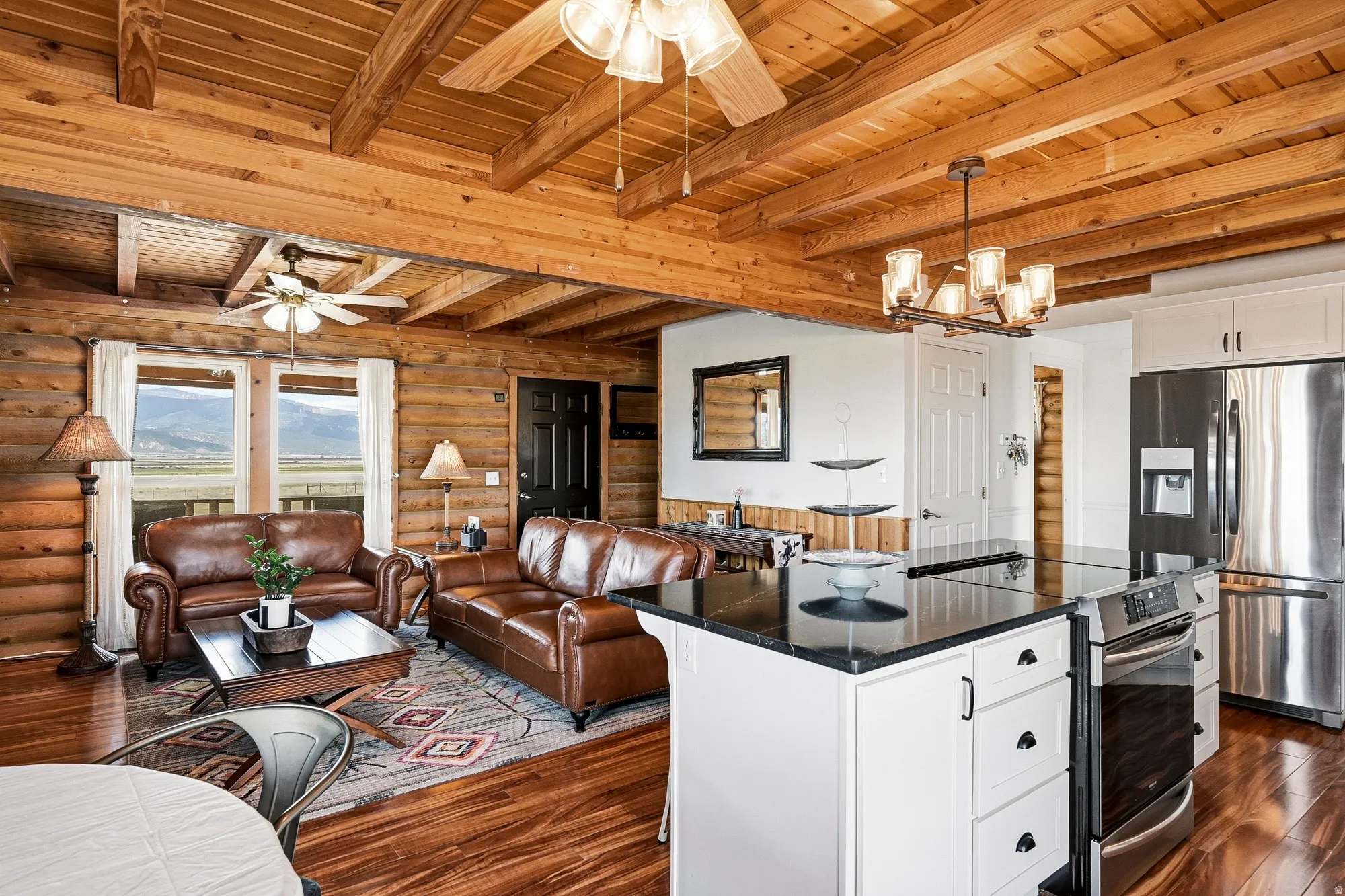 Open-concept living space featuring wood-finish flooring, exposed wood beam ceiling, and log cabin walls