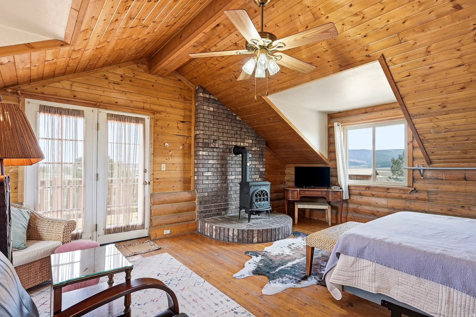 Wood-paneled room featuring a brick-backed wood-burning stove on a circular brick hearth